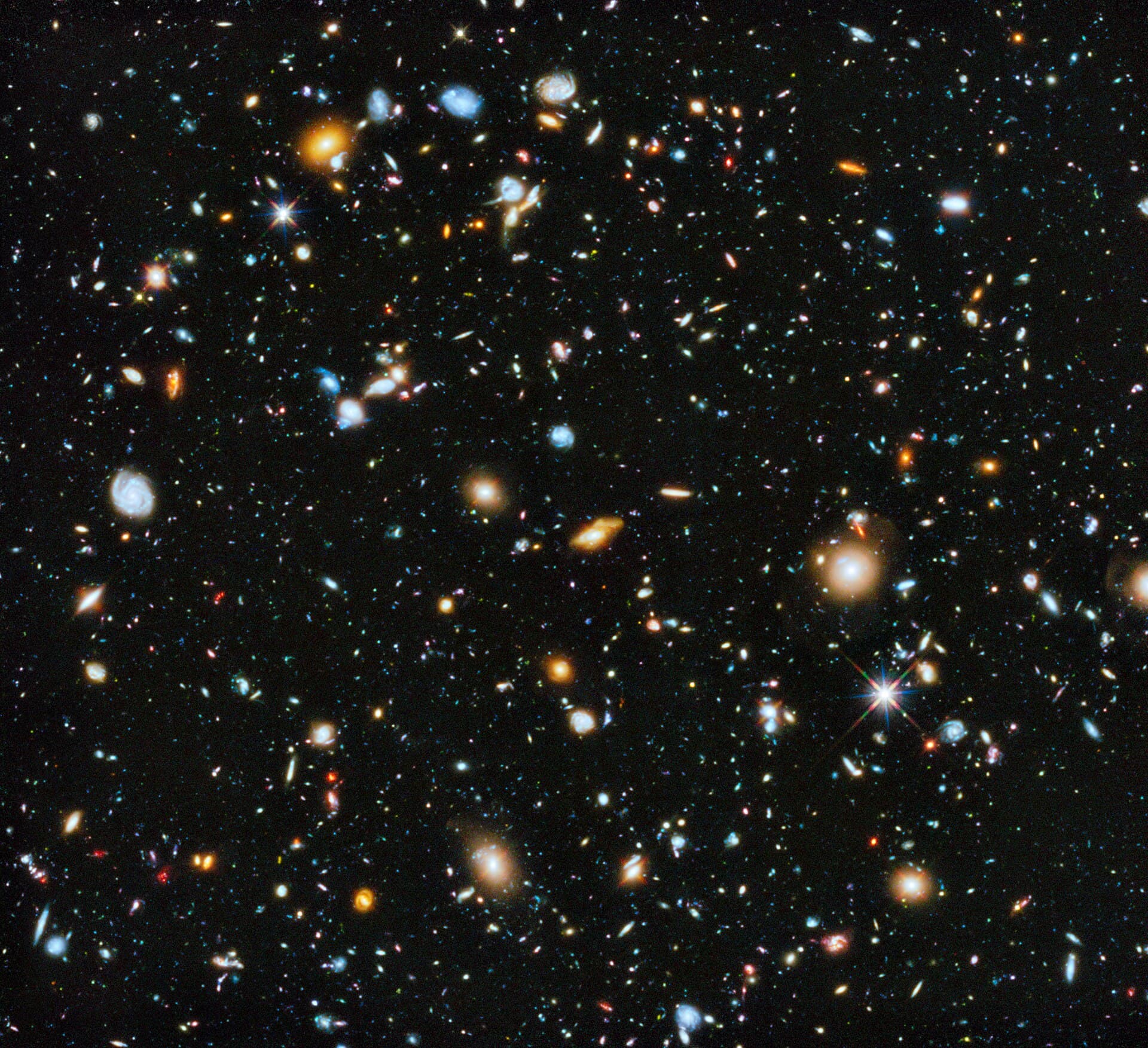 Thousands of distant galaxies of different colours and shapes scattered across black space